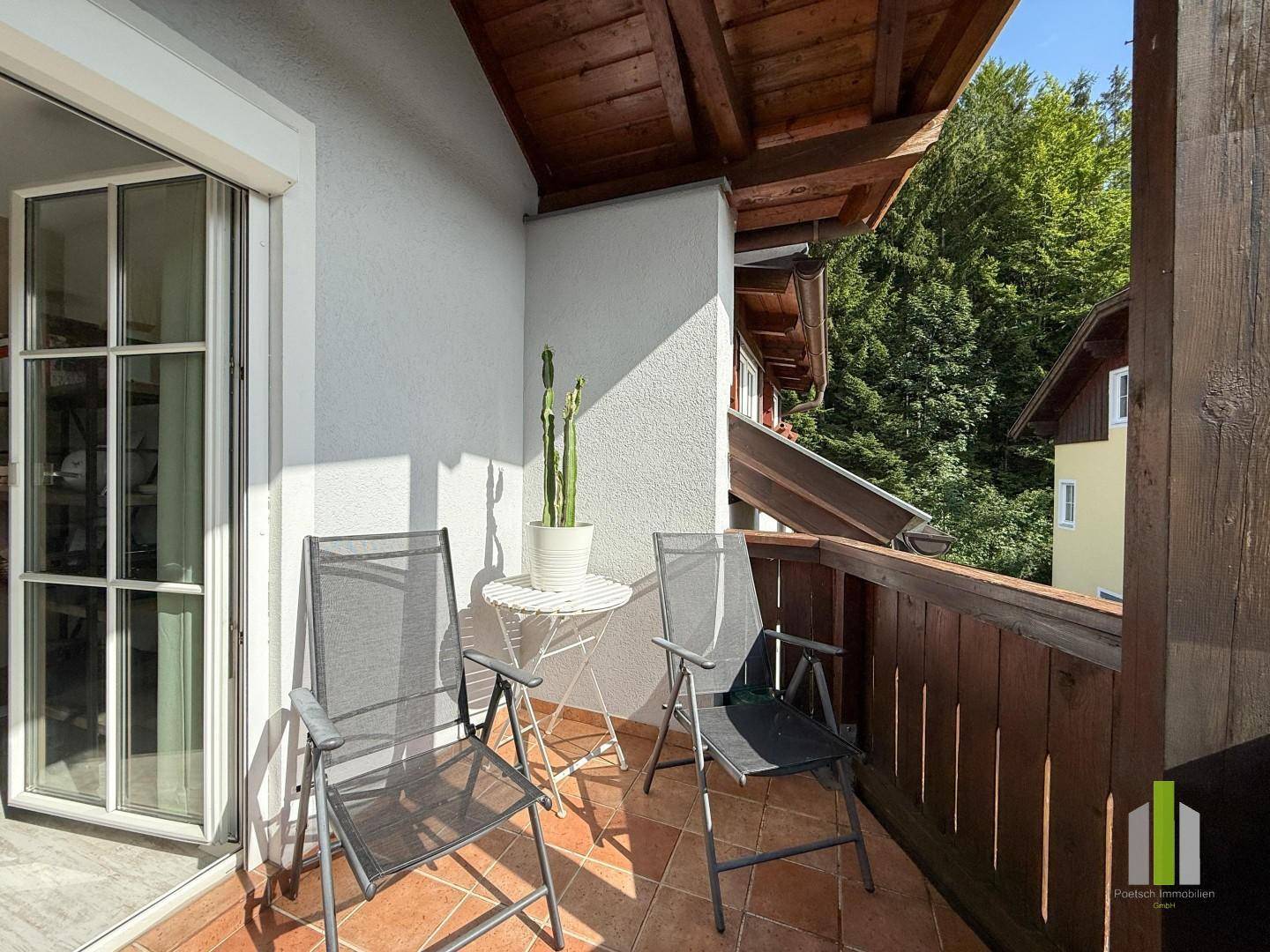 Gemütlicher Balkon mit Terracotta-Fliesen, Holzbalken und Blick ins Grüne.