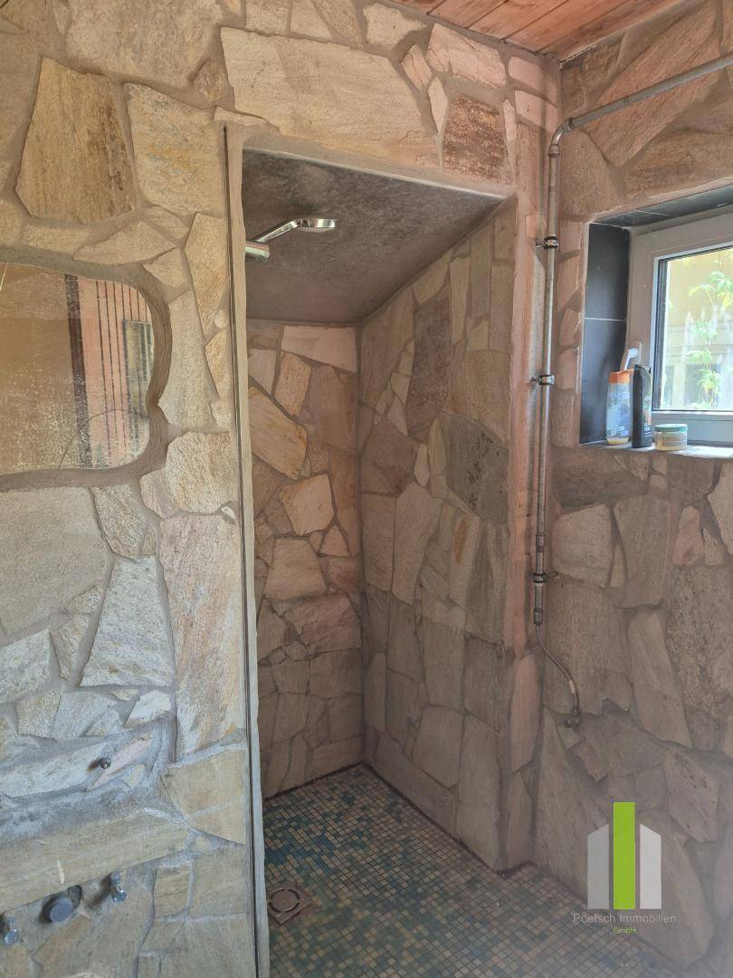 Rustikales Badezimmer mit Natursteinwänden, begehbarer Dusche und kleinem Fenster.
