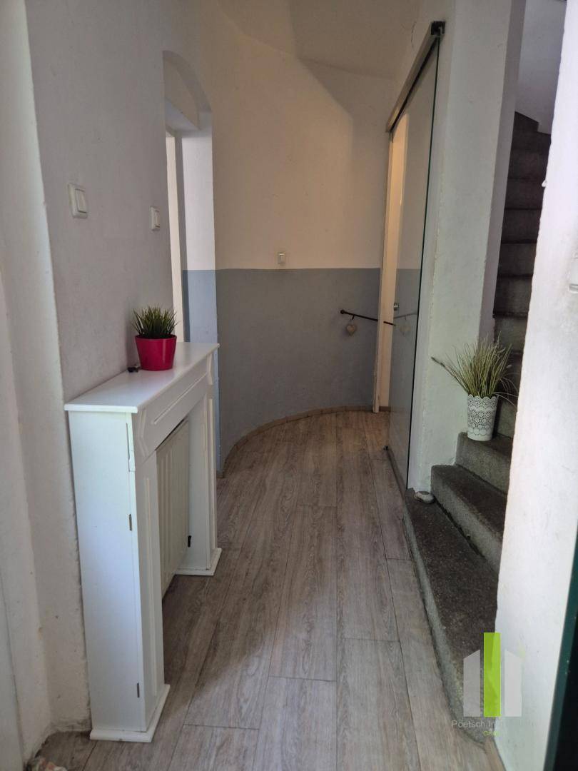 Flur mit Holzoptik-Boden, weißer Wandverkleidung und einem dekorativen Kaminsims.