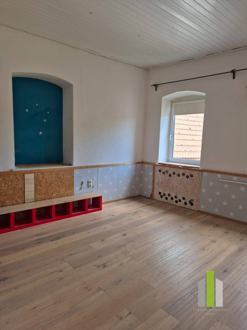 Kinderzimmer mit Holzboden, Sternenmuster-Tapete und einem blauen Nischenfenster.