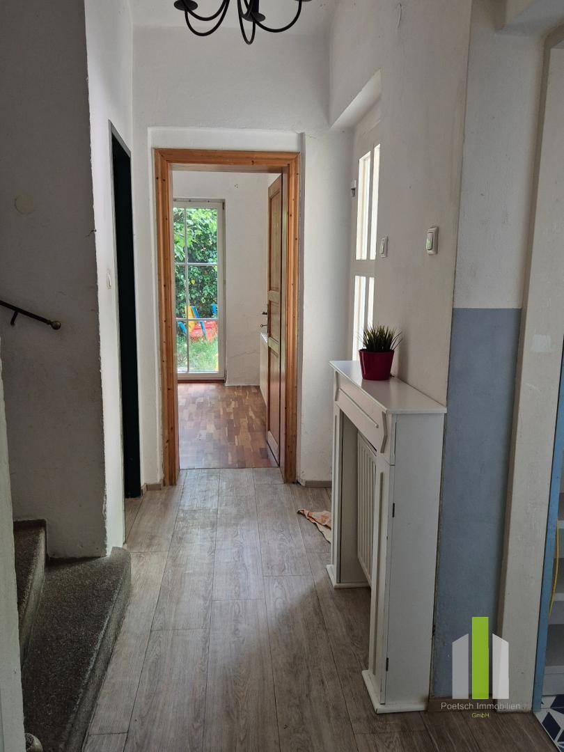 Heller Flur mit Holzoptik-Boden und Blick auf den Garten durch eine offene Tür.