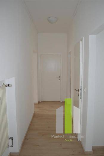 Heller Flur mit Laminatboden und weißen Wänden, verbindet die verschiedenen Räume der Wohnung.