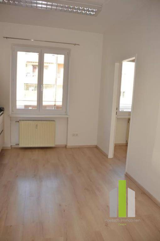 Heller Raum mit Laminatboden und großem Fenster, bietet vielseitige Nutzungsmöglichkeiten für Bewohner.