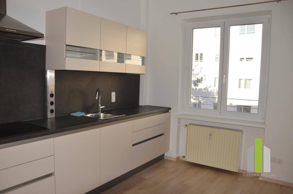 Helle Küche mit Fenster, Einbauschränken und Heizkörper, bereit für die individuelle Gestaltung und Nutzung.
