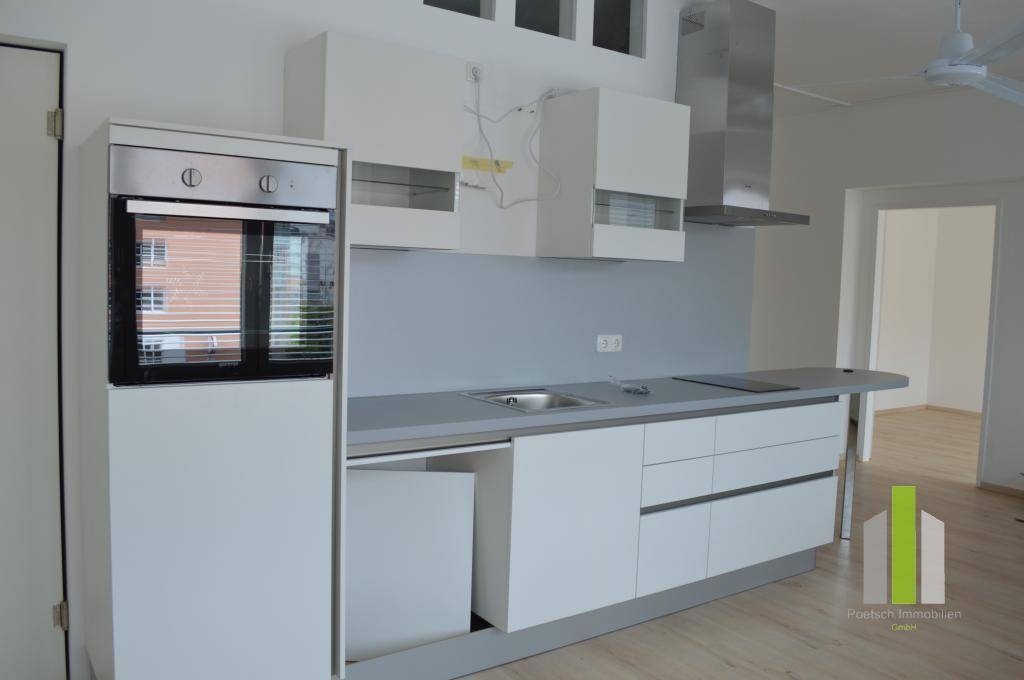 Funktionale Küche mit weißen Schränken und grauer Arbeitsfläche, inklusive Backofen und Dunstabzug.