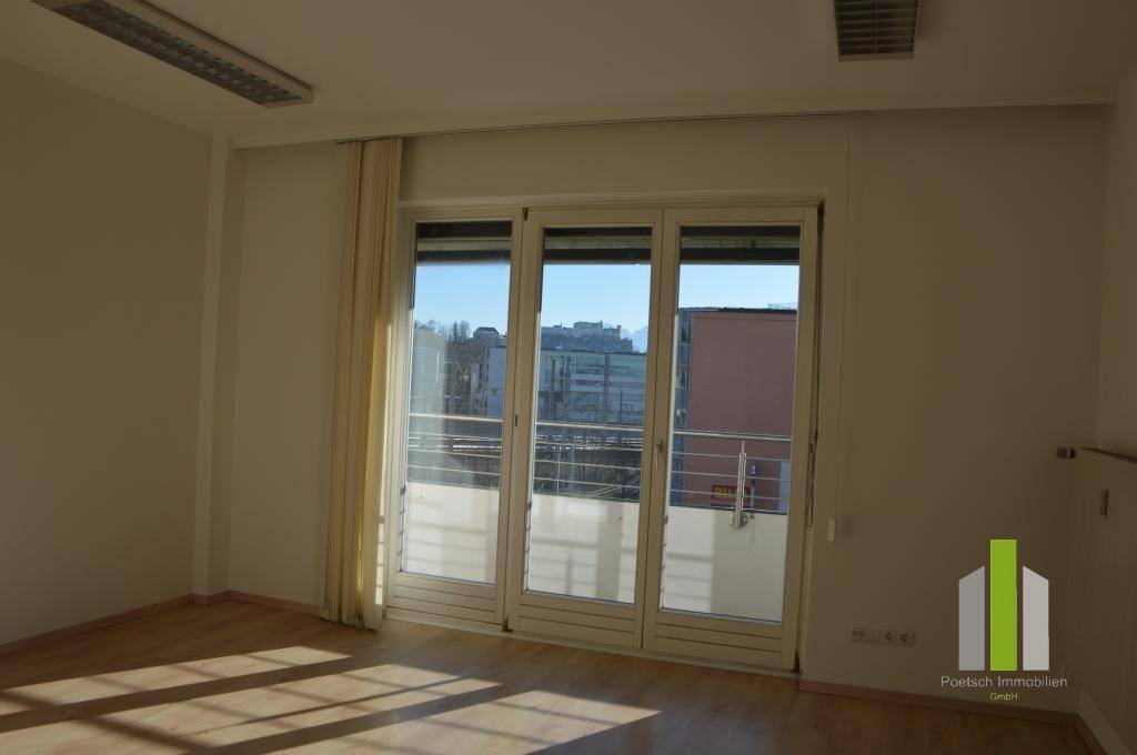 Lichtdurchfluteter Raum mit Balkonzugang und Blick auf die Stadt, ideal als gemütlicher Wohnbereich.