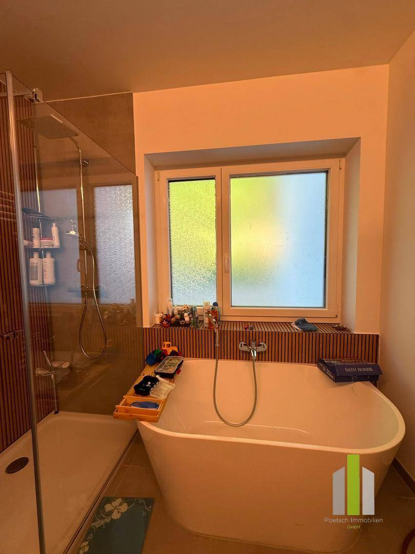 Badezimmer mit freistehender Badewanne, Duschbereich und Fenster für Tageslicht.