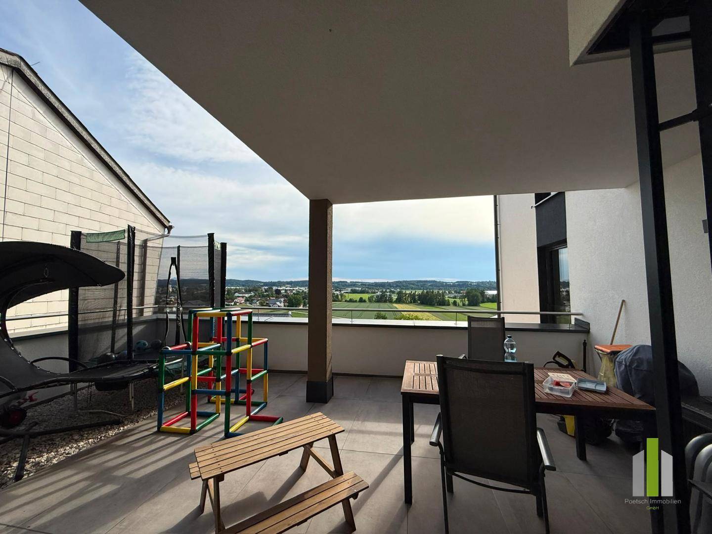 Große überdachte Terrasse mit Essbereich, Spielgeräten und weitem Ausblick.