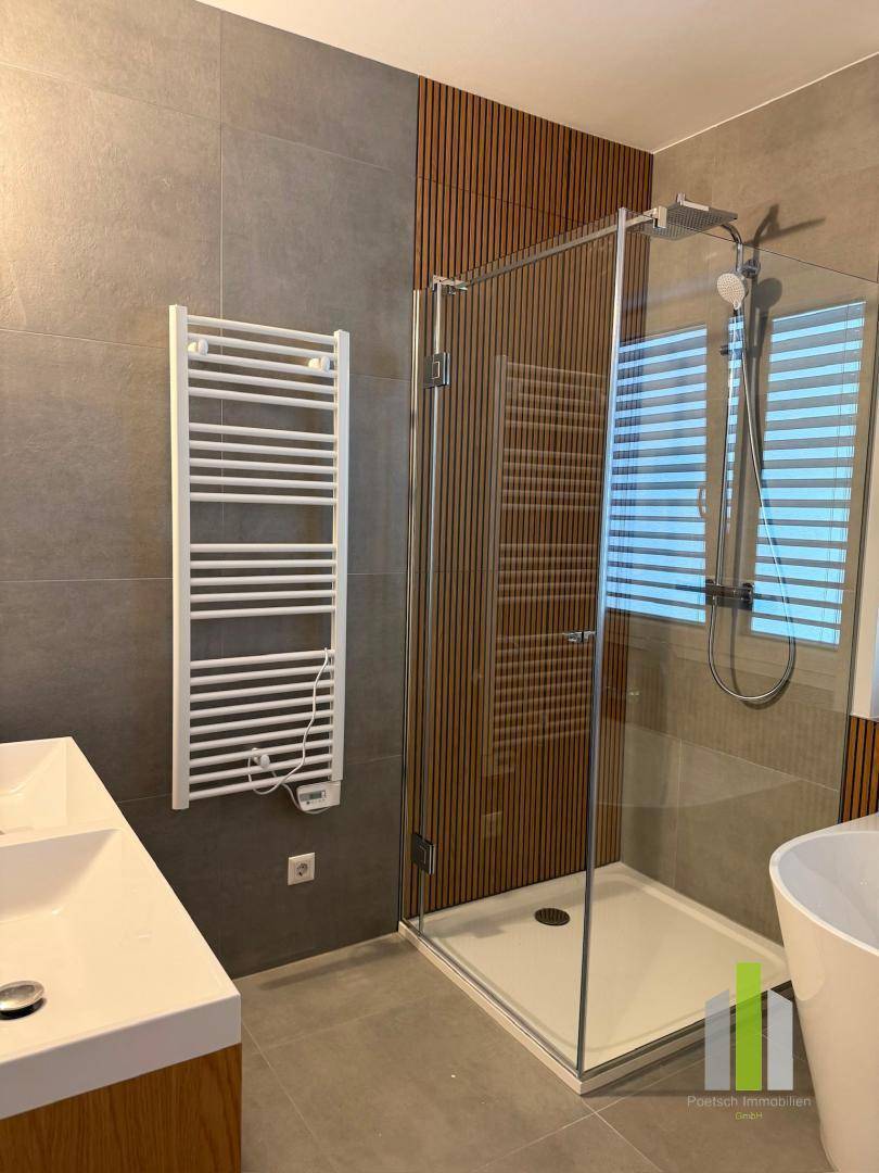 Modernes Badezimmer mit begehbarer Dusche, Doppelwaschbecken und beheiztem Handtuchhalter.
