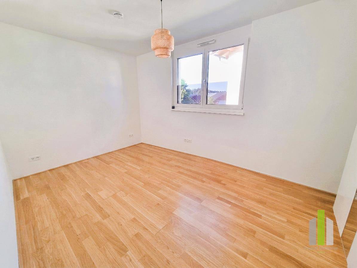 Lichtdurchflutetes Zimmer mit Parkettboden und moderner Deckenleuchte, ideal als Schlafzimmer oder Arbeitszimmer.
