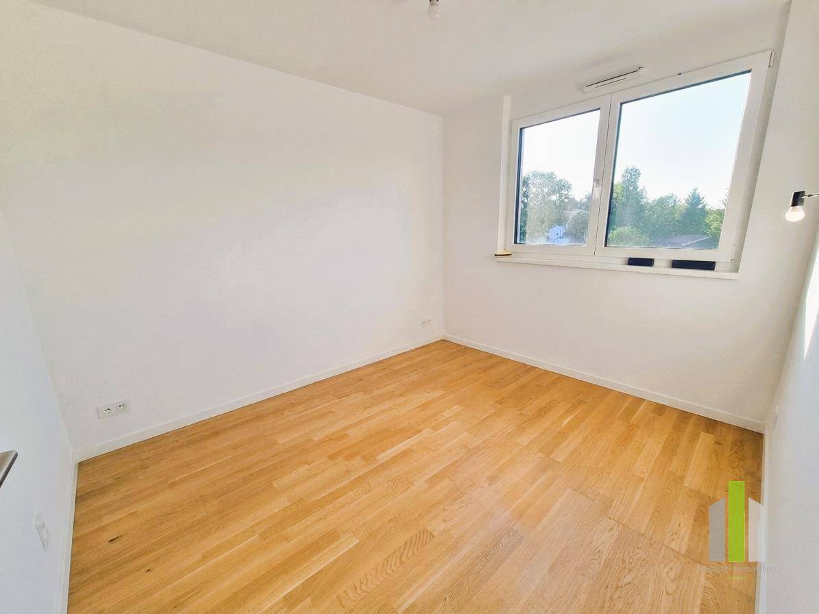 Helles Schlafzimmer mit Holzboden und großem Fenster, bietet viel Tageslicht und eine angenehme Atmosphäre.