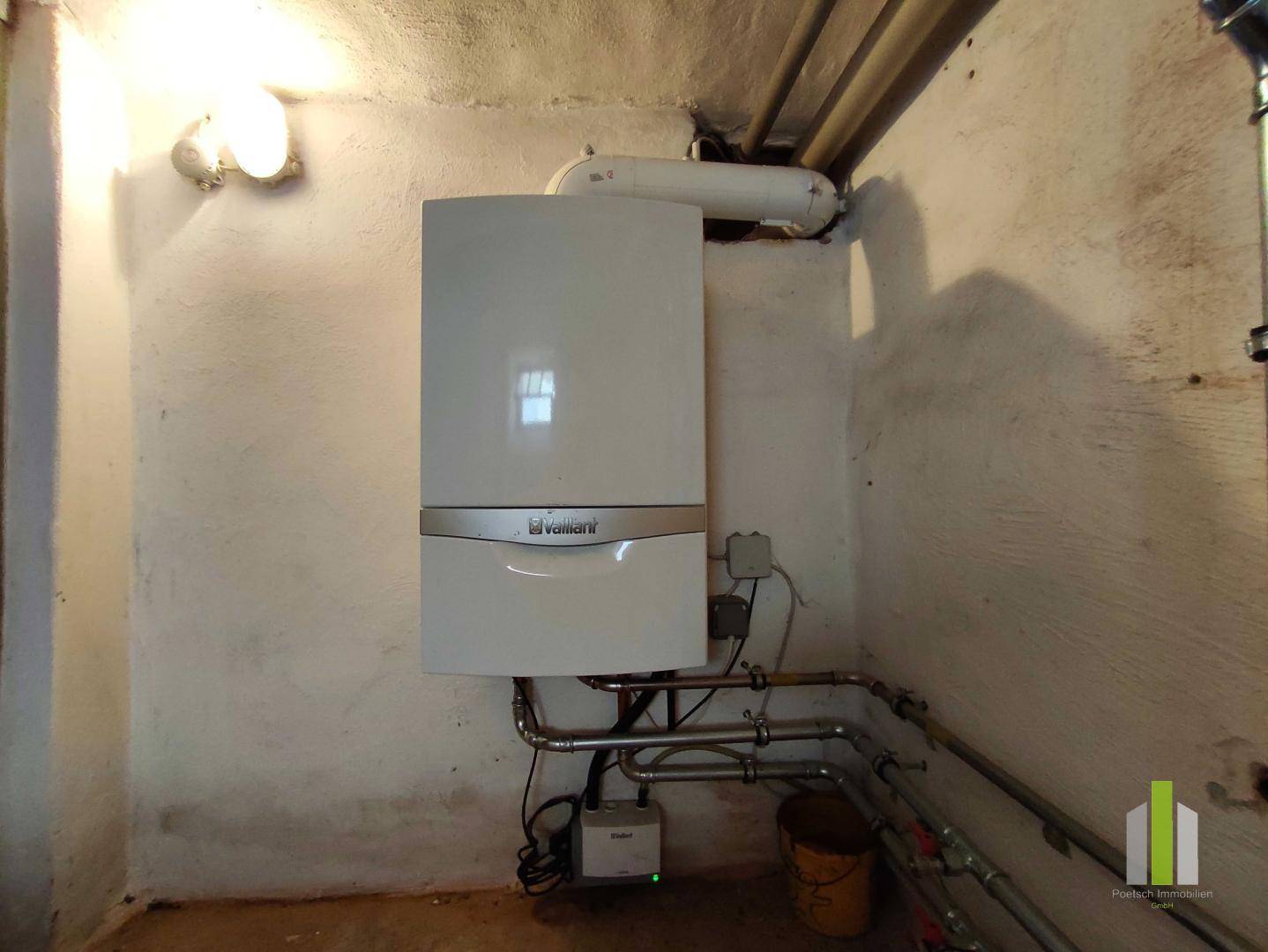 Heizungsraum im Keller mit einer modernen Vaillant Gastherme und sichtbaren Rohren.