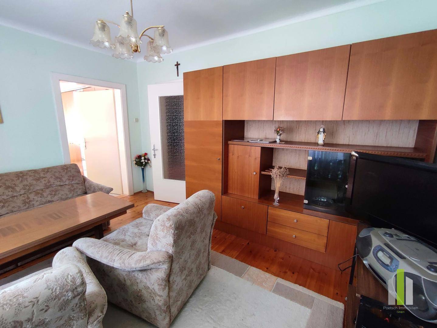 Gemütliches Wohnzimmer mit Holzmöbeln, Parkettboden und einem Sofa mit Sesseln.