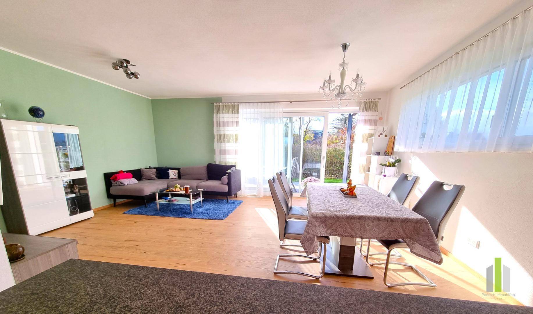 Geräumiger Wohn-Essbereich mit Zugang zur Terrasse, Holzboden und gemütlicher Sitzecke.