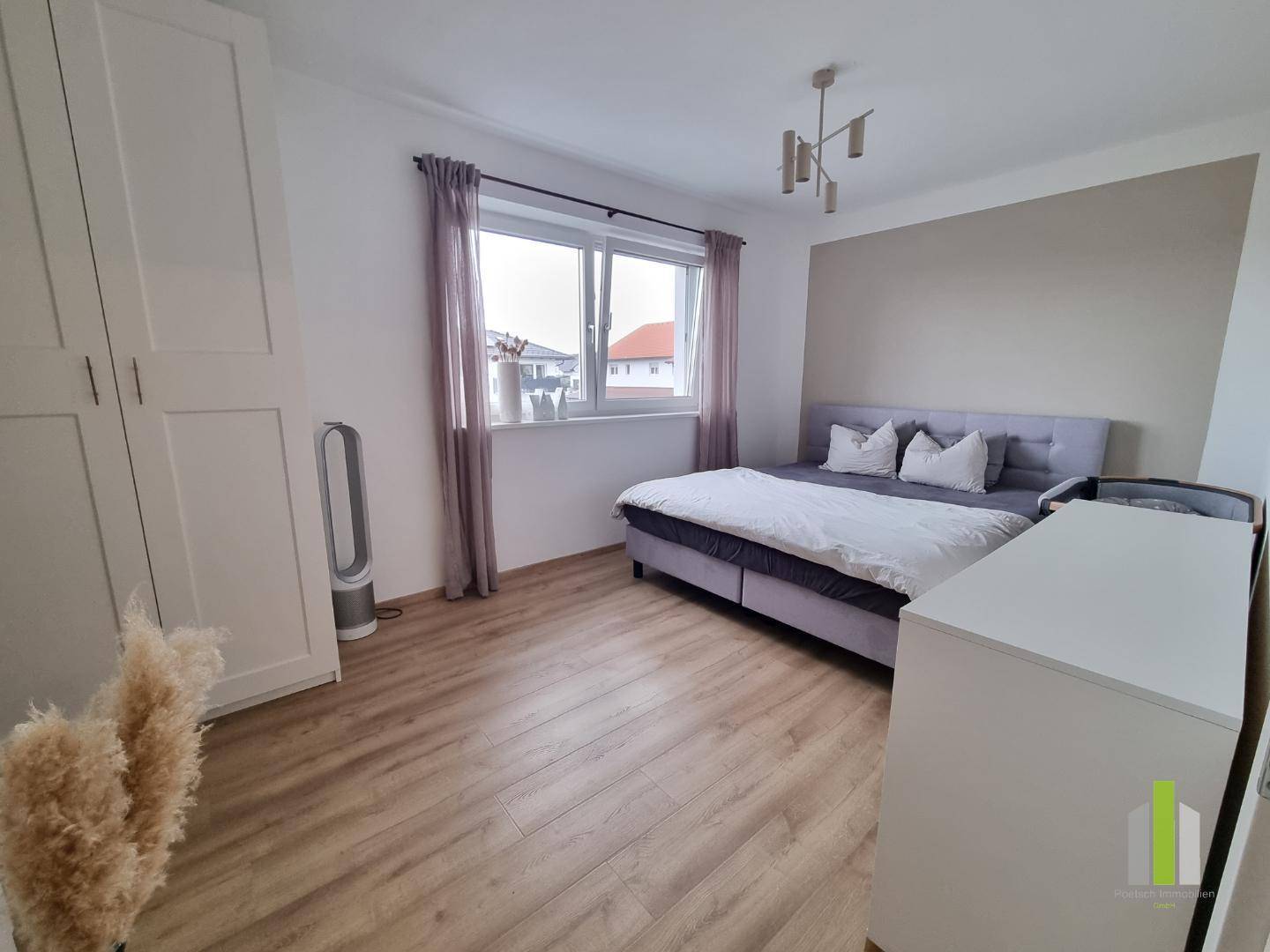Helles Schlafzimmer mit Doppelbett, weißem Kleiderschrank und Fenster, ausgestattet mit Holzboden.