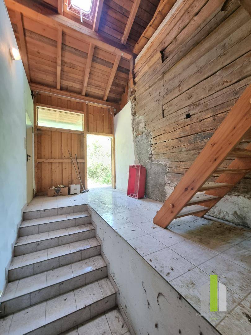 Treppenaufgang mit Fliesenboden und sichtbaren Holzbalken, der zu einem oberen Stockwerk führt.