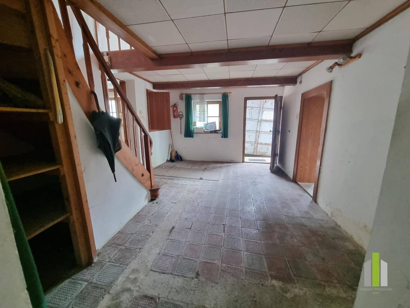 Eingangsbereich mit Holztreppe, Fliesenboden und Blick in den hinteren Bereich des Hauses.