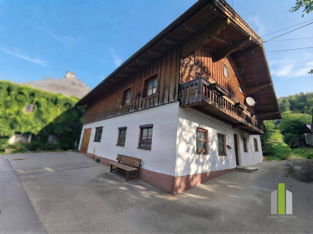 Traditionelles Haus mit Holzbalkonen und weiß verputzter Fassade unter blauem Himmel.