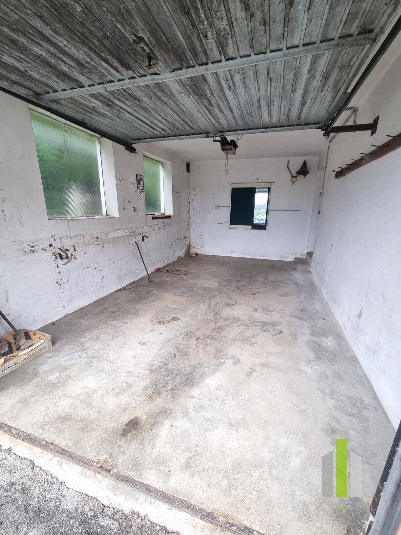 Einfache Garage mit Betonboden und Fenstern, ideal als Abstellraum oder Werkstatt.
