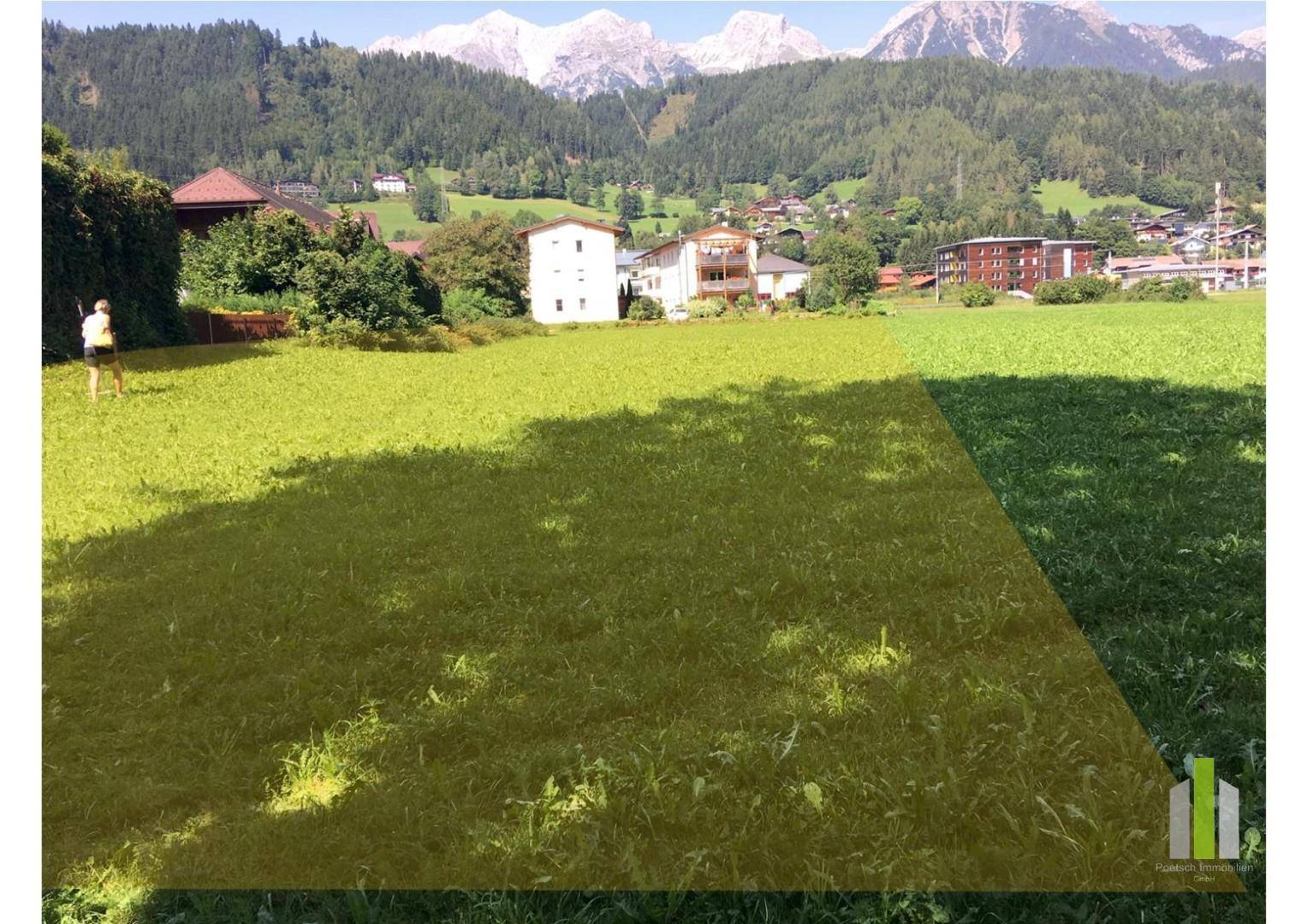 Grünes Feld mit gelb markiertem Bereich und beeindruckendem Panoramablick auf die umliegenden Berge.