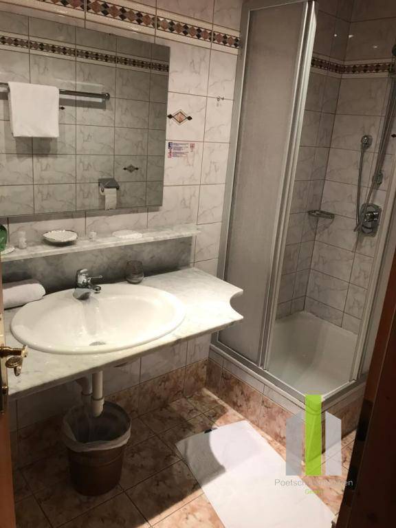 Badezimmer mit Duschkabine, Waschbecken und hellen Fliesen.