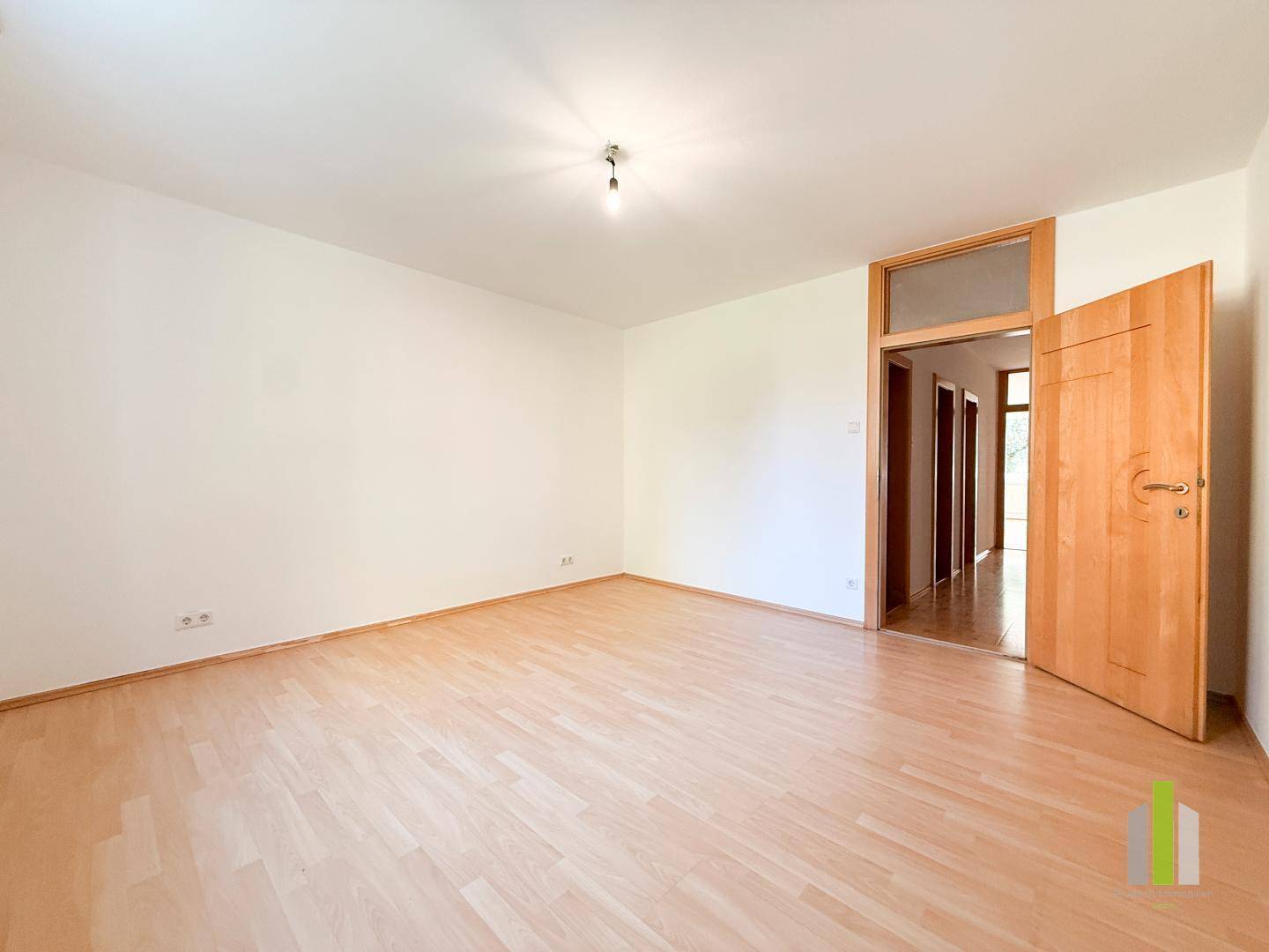 Geräumiges Schlafzimmer mit Parkettboden und Zugang zu einem angrenzenden Flur.