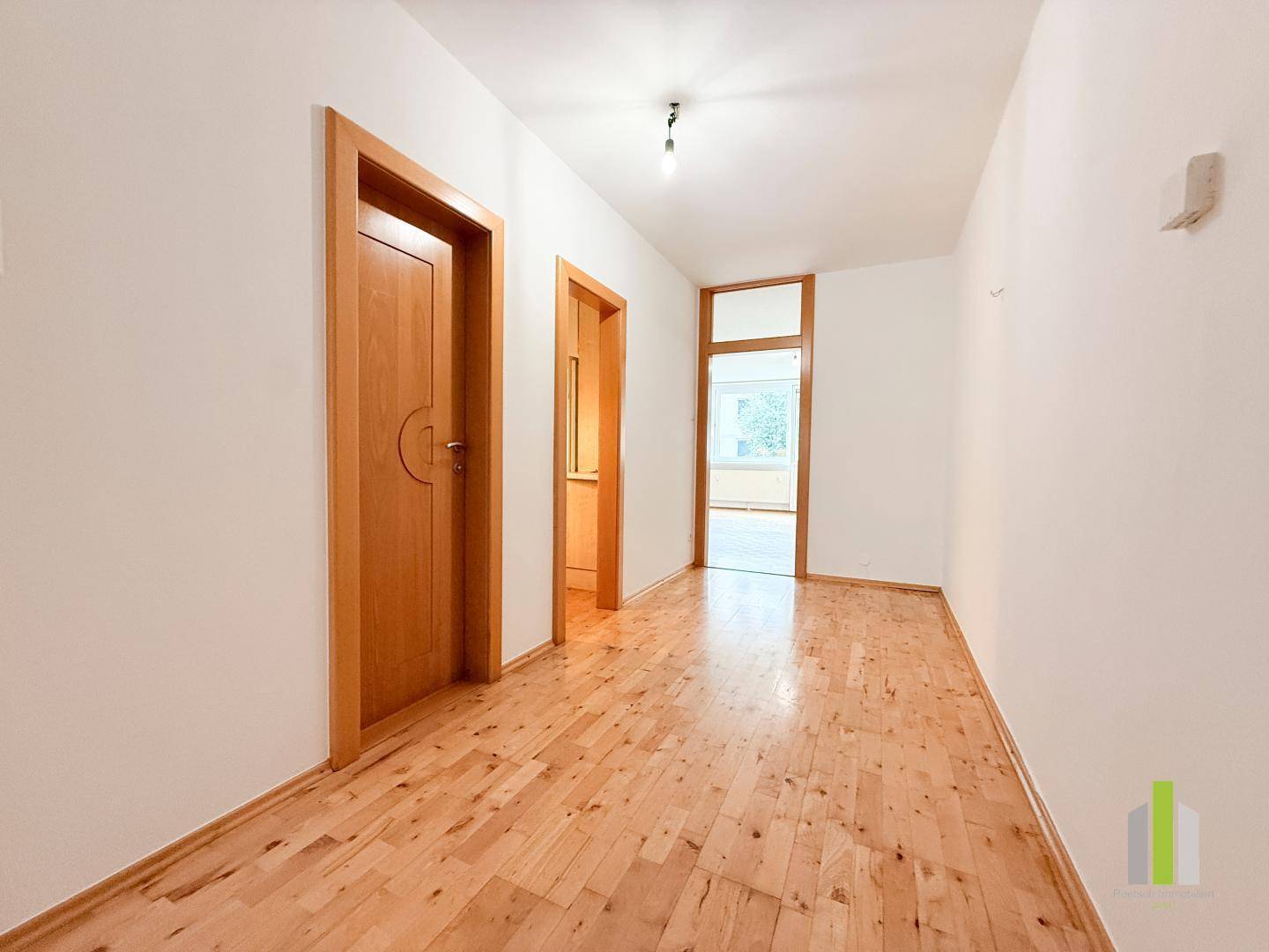 Heller Flur mit Holzparkett und mehreren Holztüren, die zu den angrenzenden Räumen führen.