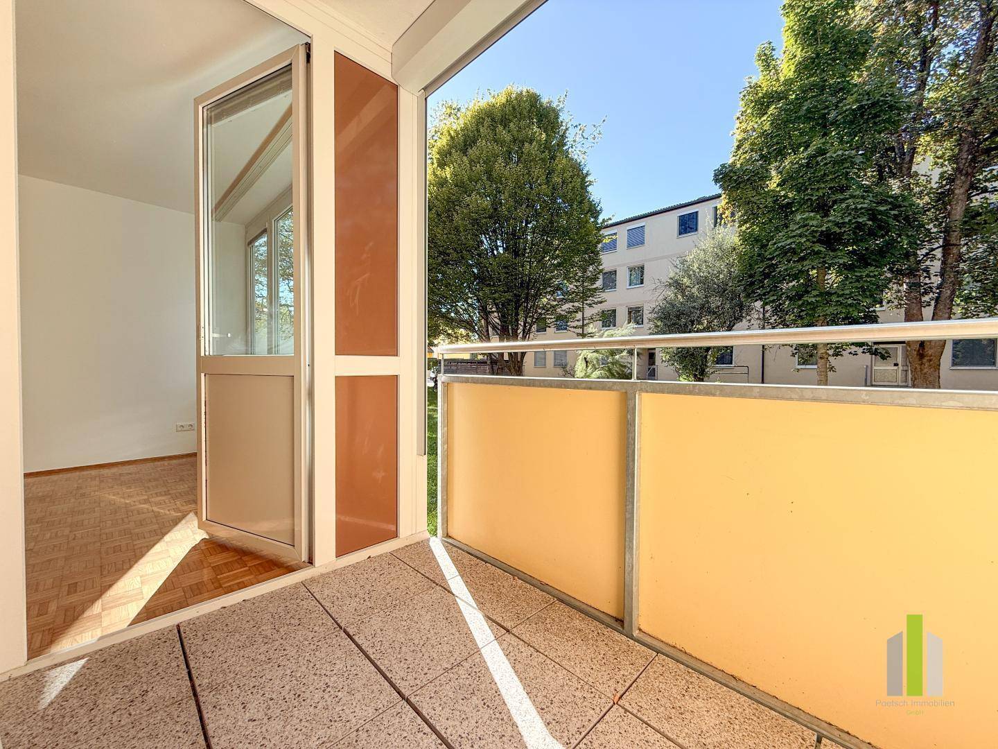 Sonniger Balkon mit Fliesenboden und Blick ins Grüne, ideal zum Entspannen im Freien.