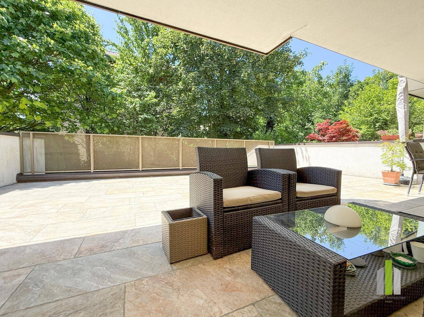 Gemütlicher Sitzbereich auf der Terrasse mit Rattanmöbeln und grüner Umgebung.