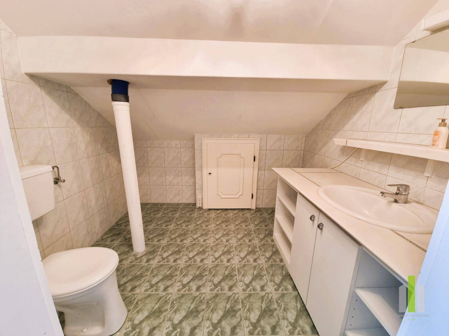 Kleines WC im Dachgeschoss mit Waschbecken, Toilette und schrägen Wänden.