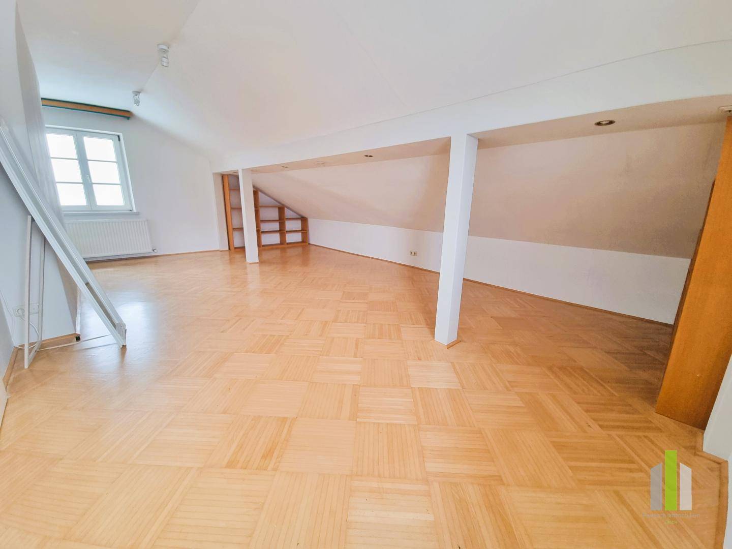 Geräumiger Dachbodenraum mit Holzboden, schrägen Wänden und natürlichem Lichteinfall.