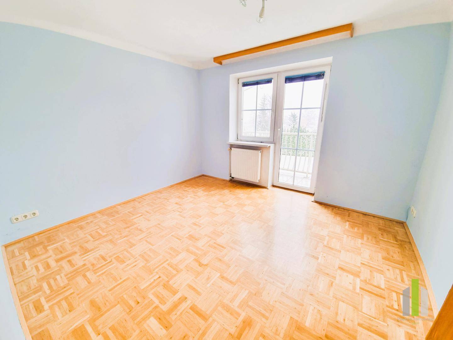 Gemütliches Schlafzimmer mit hellblau gestrichenen Wänden und Parkettboden.