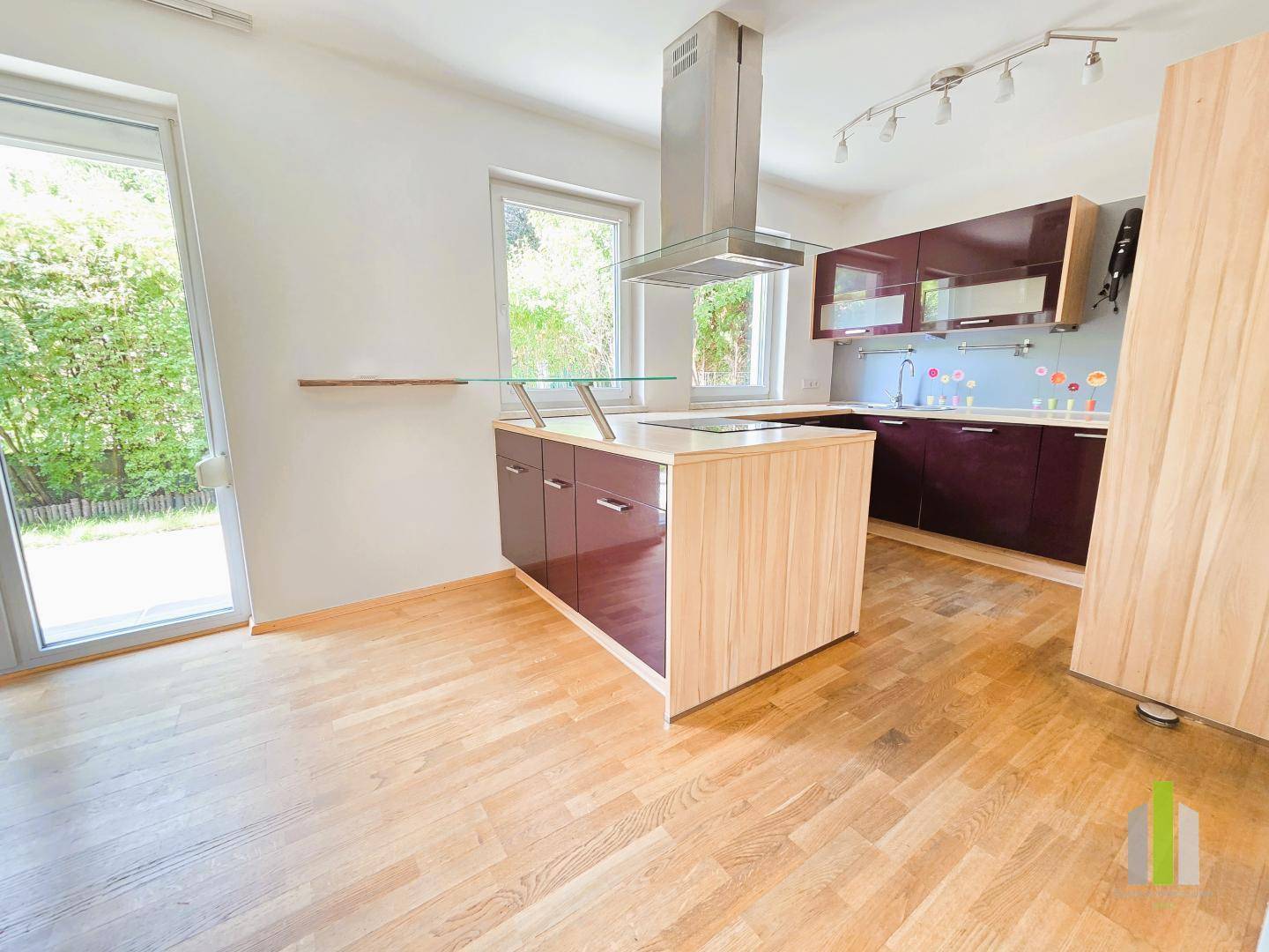 Moderne Einbauküche mit Kochinsel, Dunstabzugshaube und direktem Zugang zum Garten.