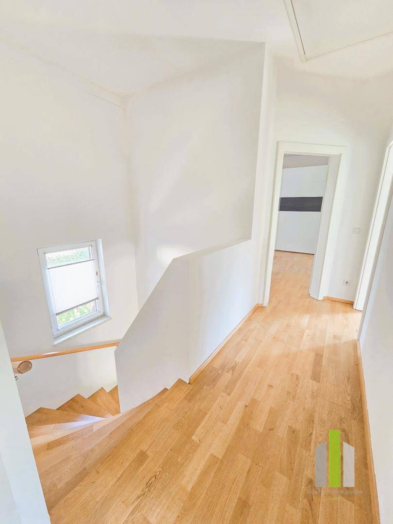 Heller Flur mit Holztreppe und Holzboden, der die verschiedenen Ebenen des Hauses verbindet.