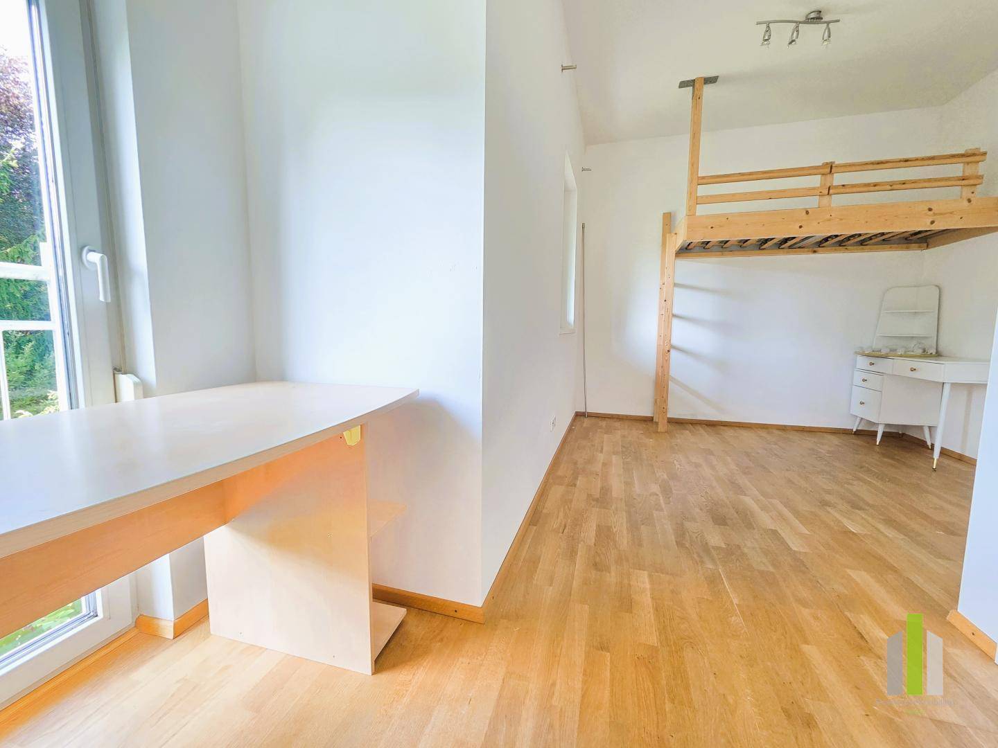 Geräumiges Zimmer mit Holzboden, Hochbett und Schreibtisch, ideal als Kinder- oder Arbeitszimmer.
