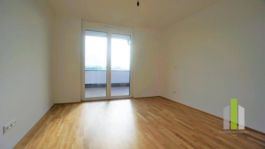 Geräumiges Schlafzimmer mit Holzboden und direktem Zugang zu einem Balkon oder einer Terrasse.