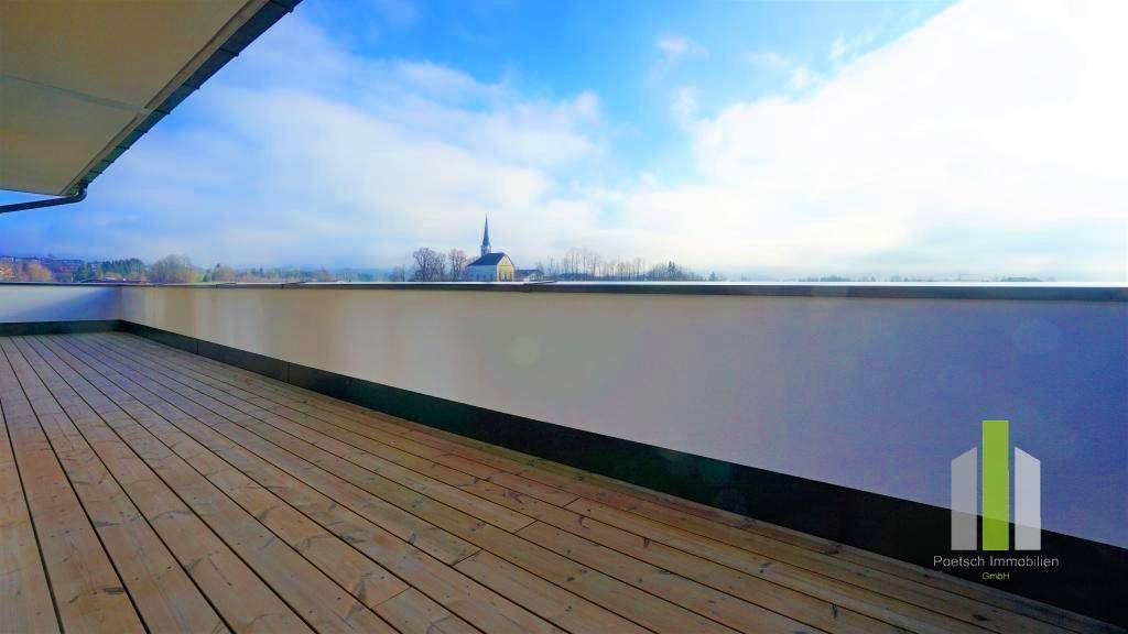Weitläufige Dachterrasse mit Holzdielen und einem Panoramablick auf die weite Landschaft.