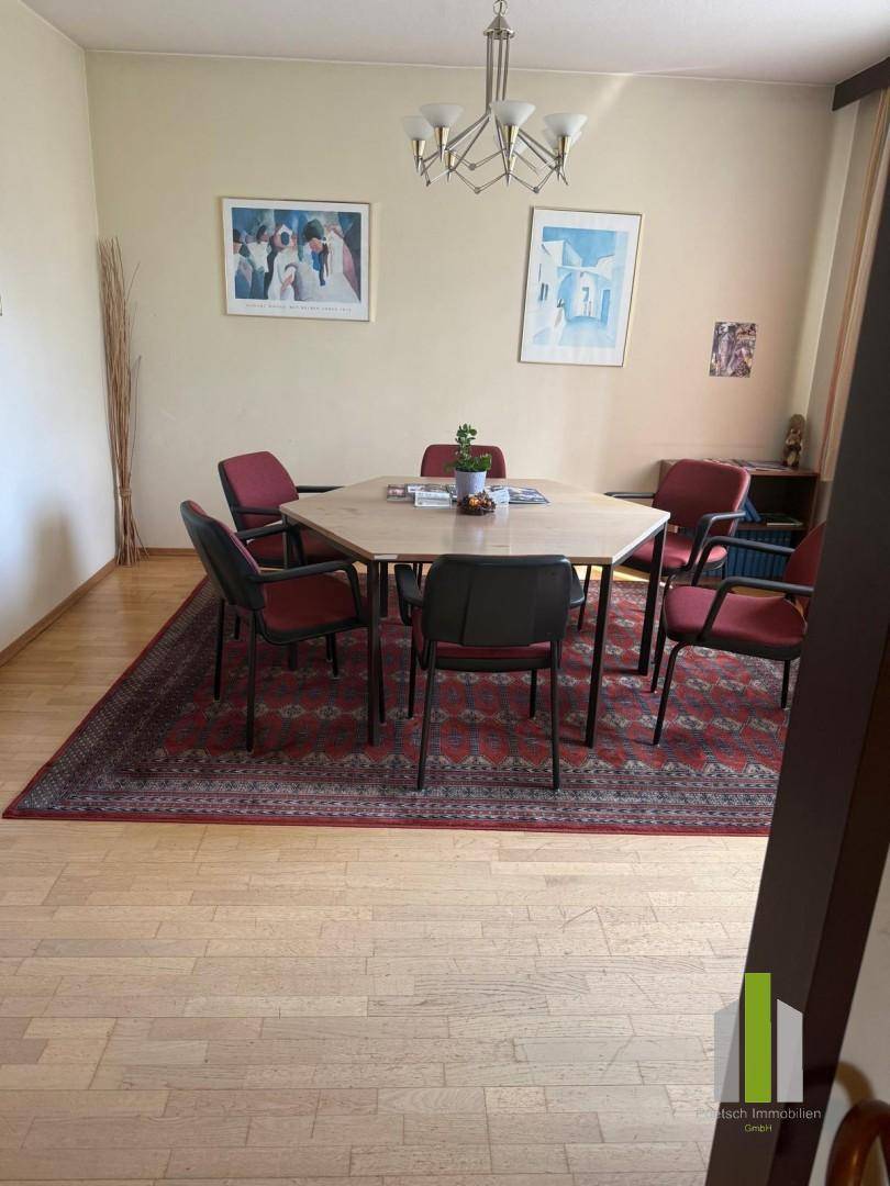 Besprechungsraum mit einem großen Tisch, mehreren Stühlen und Bildern an den Wänden.