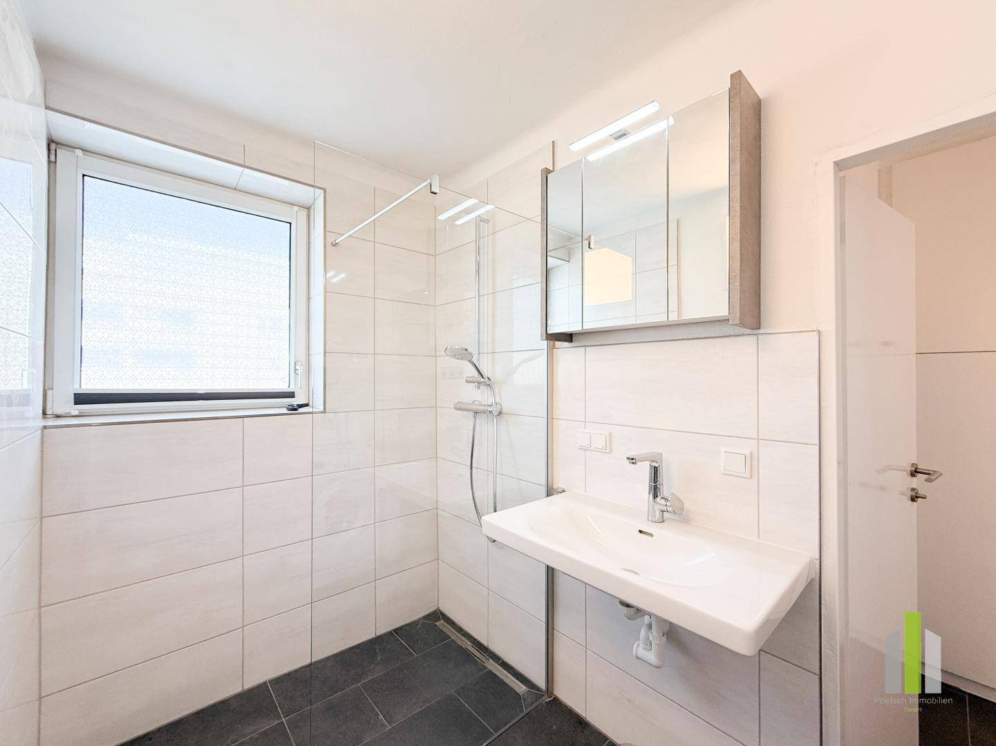 Modernes Badezimmer mit ebenerdiger Dusche, Waschbecken, Spiegelschrank und Fenster.