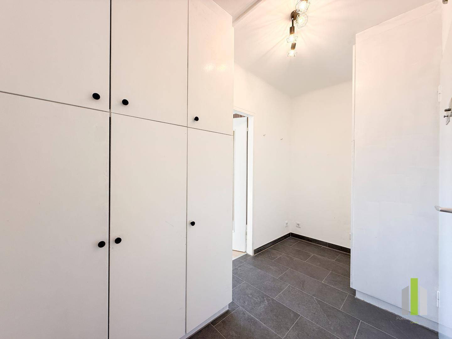 Flur mit praktischen Einbauschränken und dunklem Fliesenboden, der zusätzlichen Stauraum im Eingangsbereich schafft.