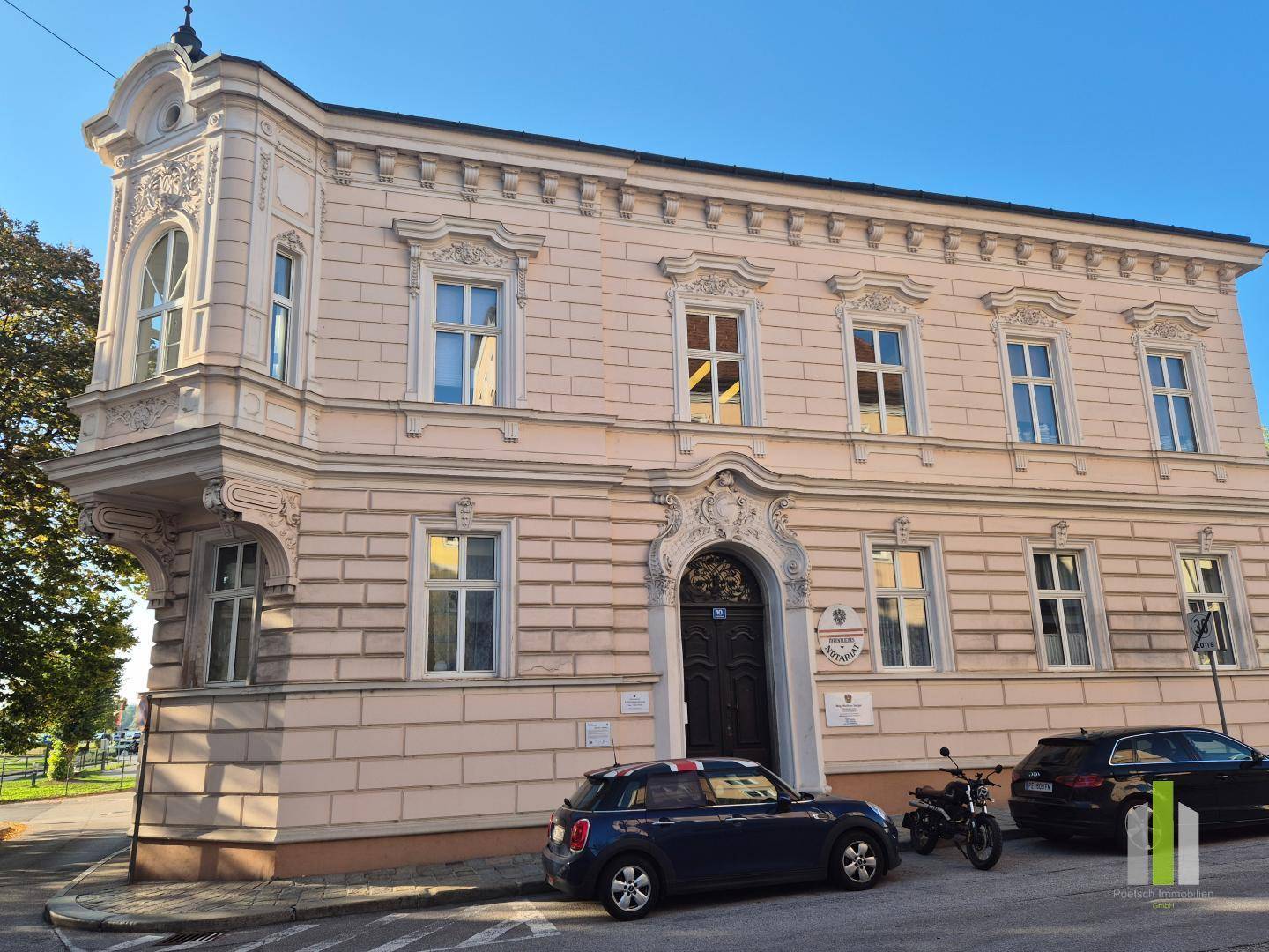 Historisches Gebäude mit eleganter Fassade, Erker und Eingangsbereich, geparkt sind Autos.