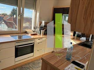 Helle Küche mit Holzarbeitsplatten, Einbaugeräten und Fenster mit Blick nach draußen.