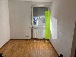 Leeres Zimmer mit Holzboden und Fenster, ideal als Schlaf- oder Arbeitszimmer.