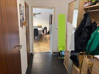 Flur mit dunklen Fliesen, Garderobe und Zugang zum Wohnbereich.