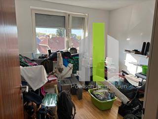 Unaufgeräumter Raum mit Holzboden und Fenster, dessen genaue Funktion unklar ist.