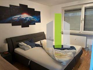 Schlafzimmer mit Doppelbett, Holzboden und Fenster mit Jalousien.