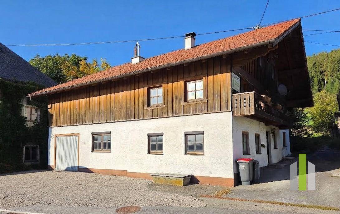 Ansicht des traditionellen Hauses mit Holzbalkon und gepflegter Fassade unter blauem Himmel.