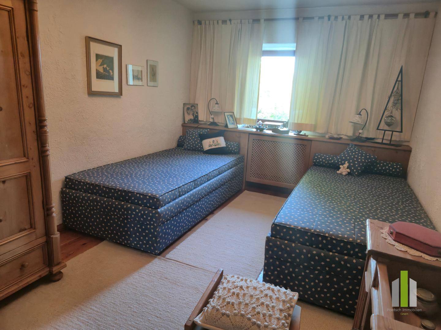 Schlafzimmer mit zwei Einzelbetten, Holzboden und traditionellem Holzschrank.