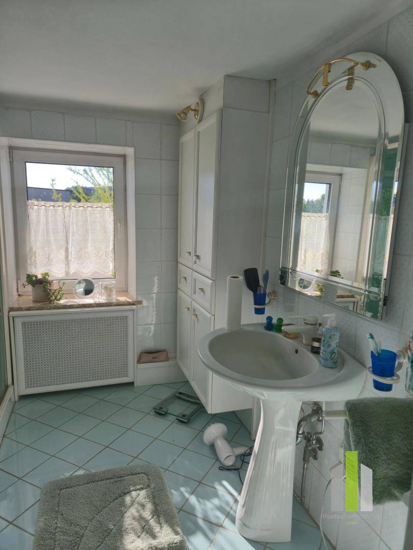 Badezimmer mit hellblauen Fliesen, Waschtisch und Fenster für Tageslicht, im Stil der 80er Jahre.