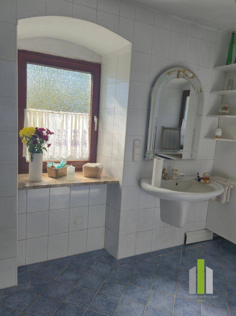 Helles Badezimmer mit blauen Fliesen, Fenster und traditionellem Waschbecken.